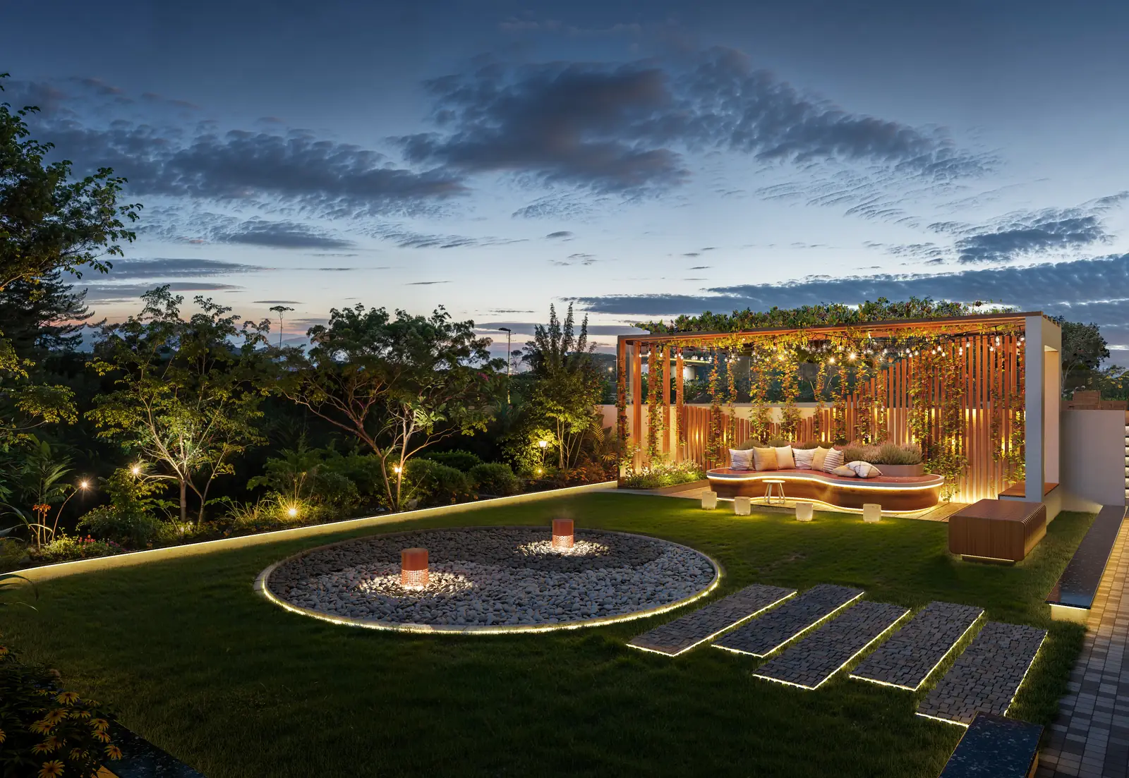 Landscaped lawn at dusk with a lit pergola sit-out and a circular fire pit